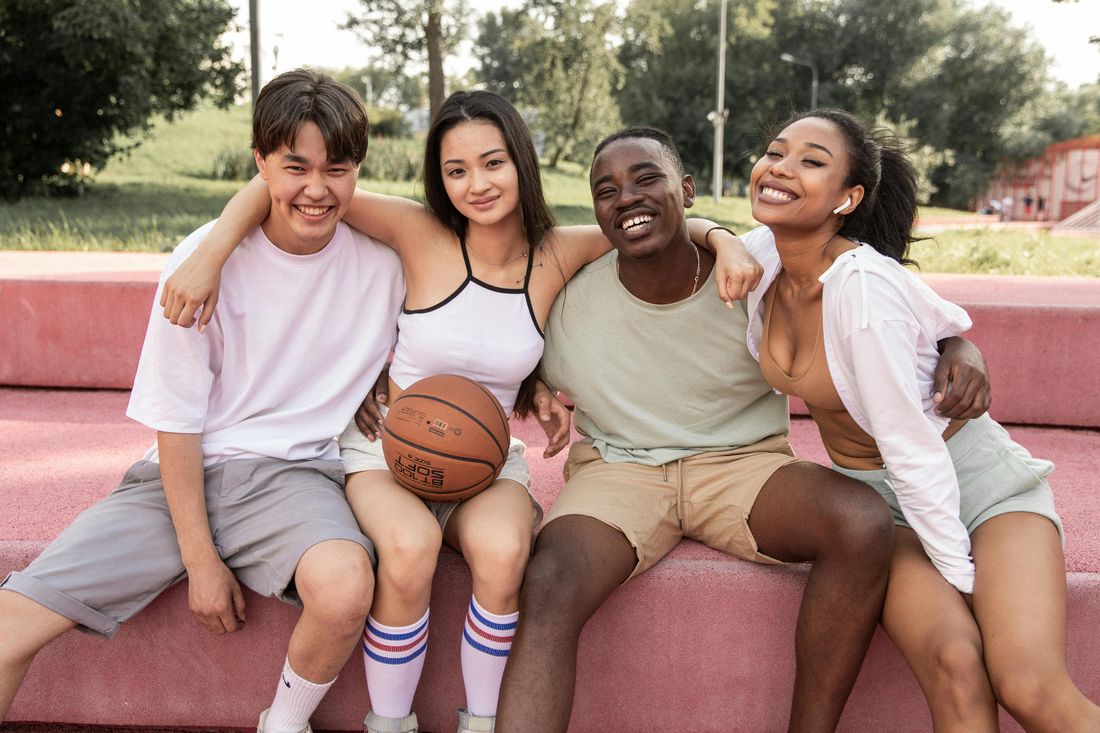 Four friends sitting together on a basketball court after a game