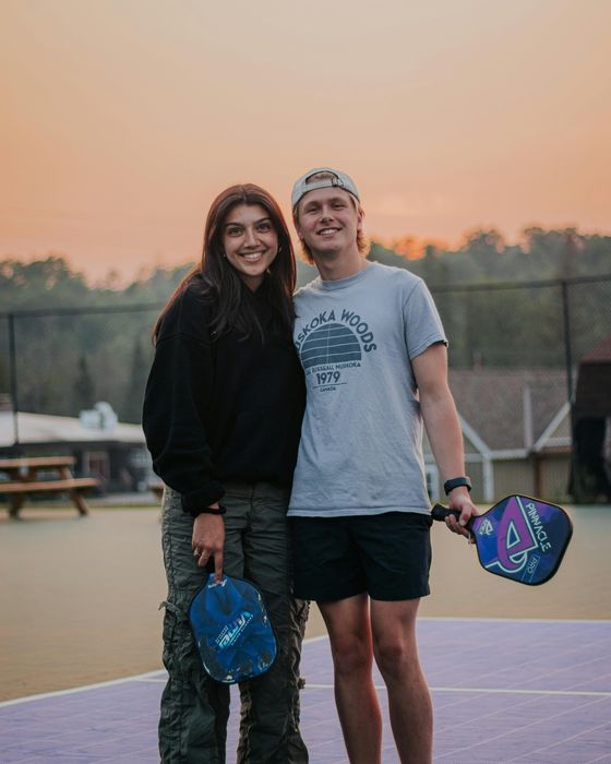 Two friends with pickleball paddles at sunset